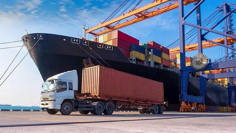 Container truck at the port beside a cargo ship
